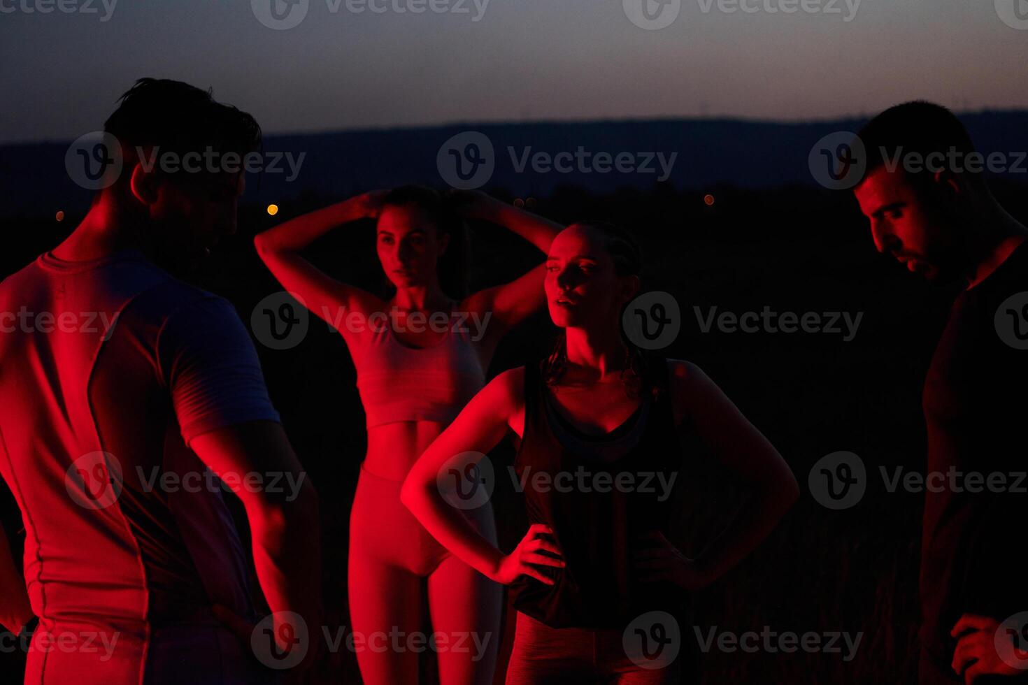 Diverse Athletes Unwind. Post-Marathon Rest Under Red Nighttime Glow. photo