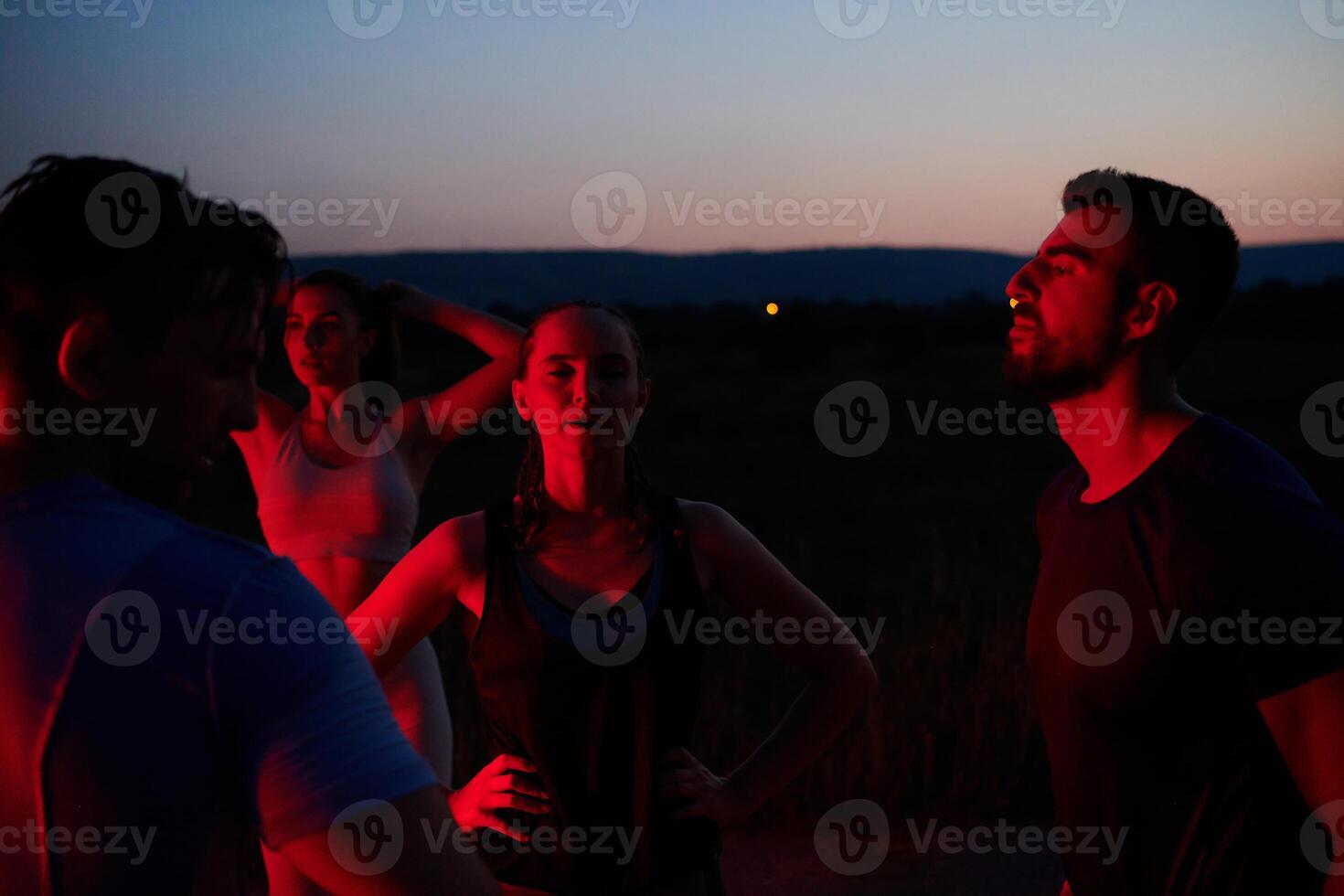 Diverse Athletes Unwind. Post-Marathon Rest Under Red Nighttime Glow. photo