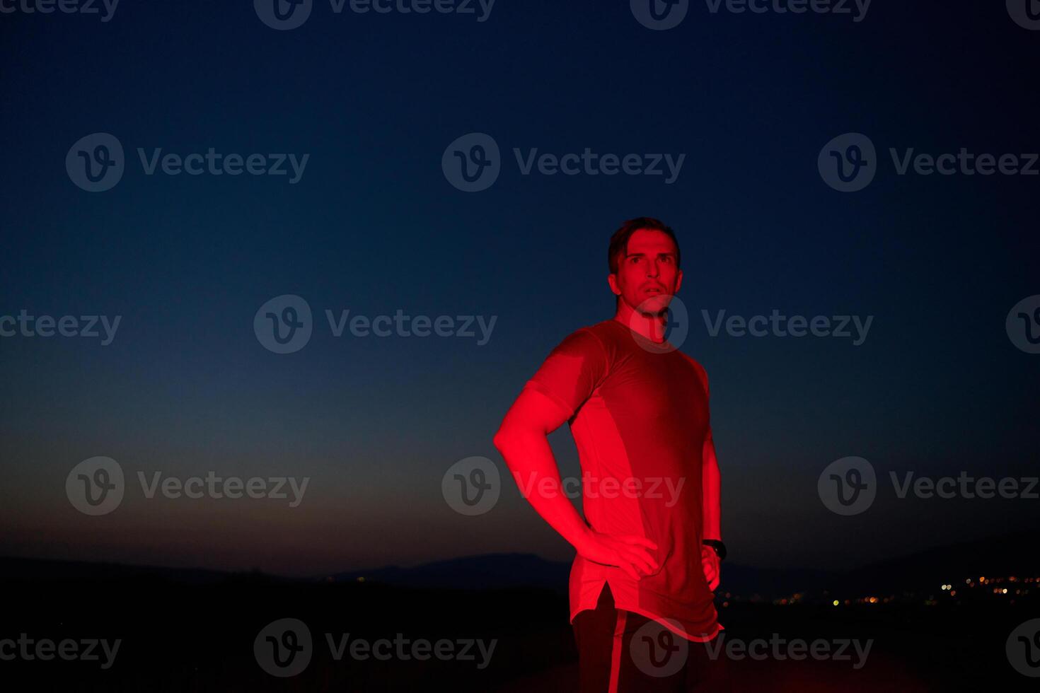 Athlete Strikes a Pose Under Red Nighttime Glow After Intense Daylong Marathon. photo