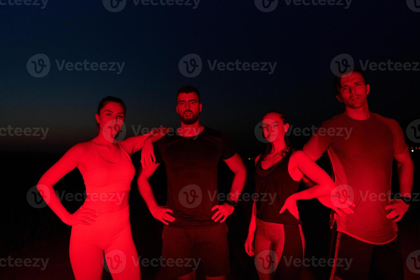 Diverse Athletes Unwind. Post-Marathon Rest Under Red Nighttime Glow. photo