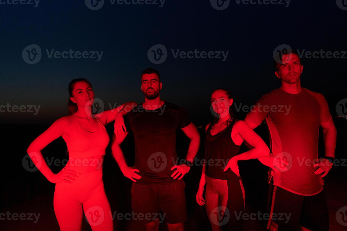 Diverse Athletes Unwind. Post-Marathon Rest Under Red Nighttime Glow. photo