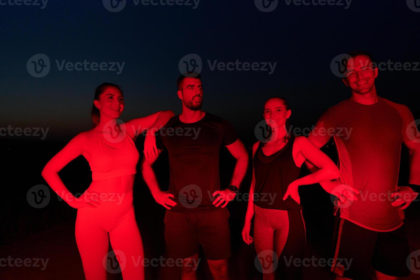 Diverse Athletes Unwind. Post-Marathon Rest Under Red Nighttime Glow. photo