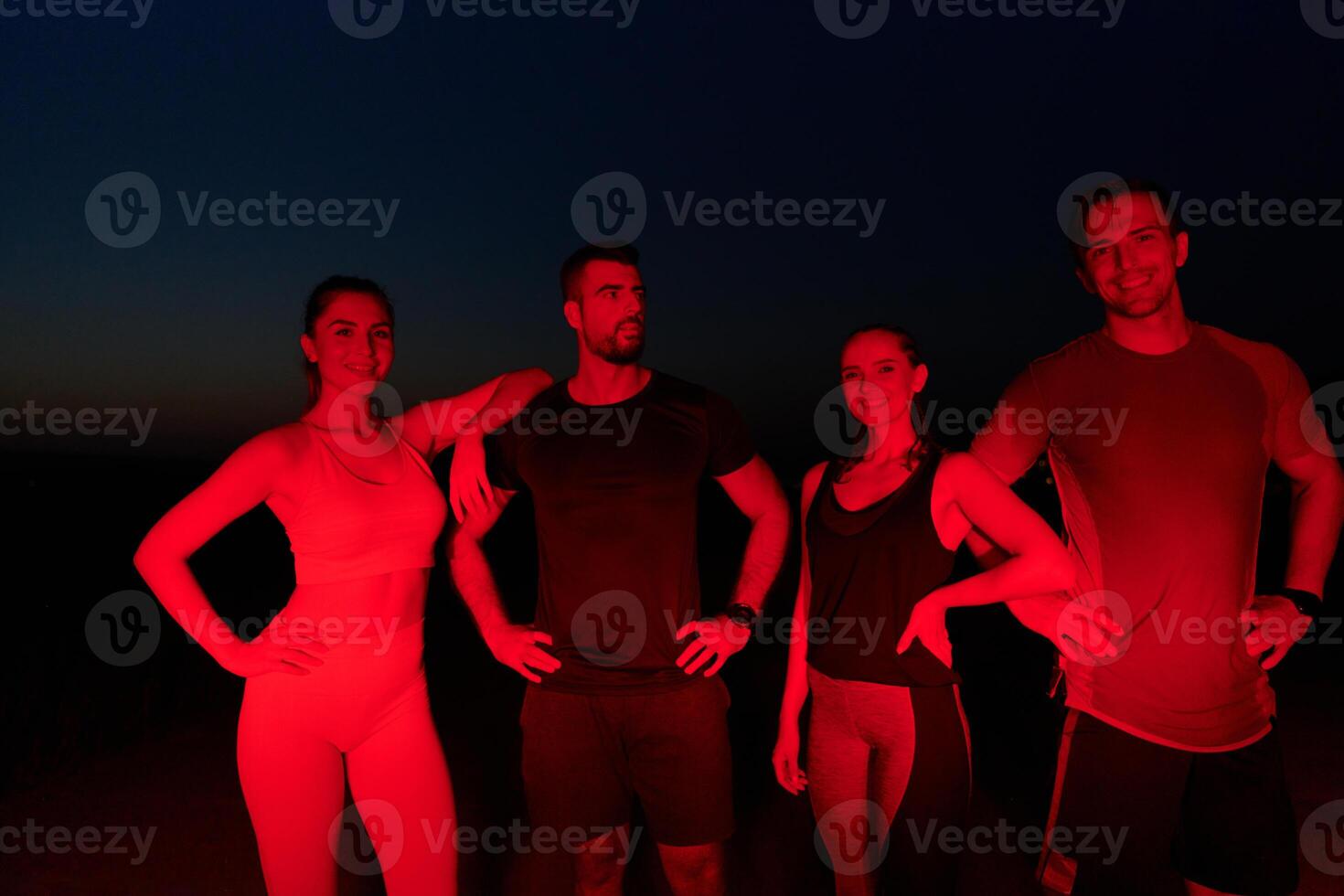 Diverse Athletes Unwind. Post-Marathon Rest Under Red Nighttime Glow. photo