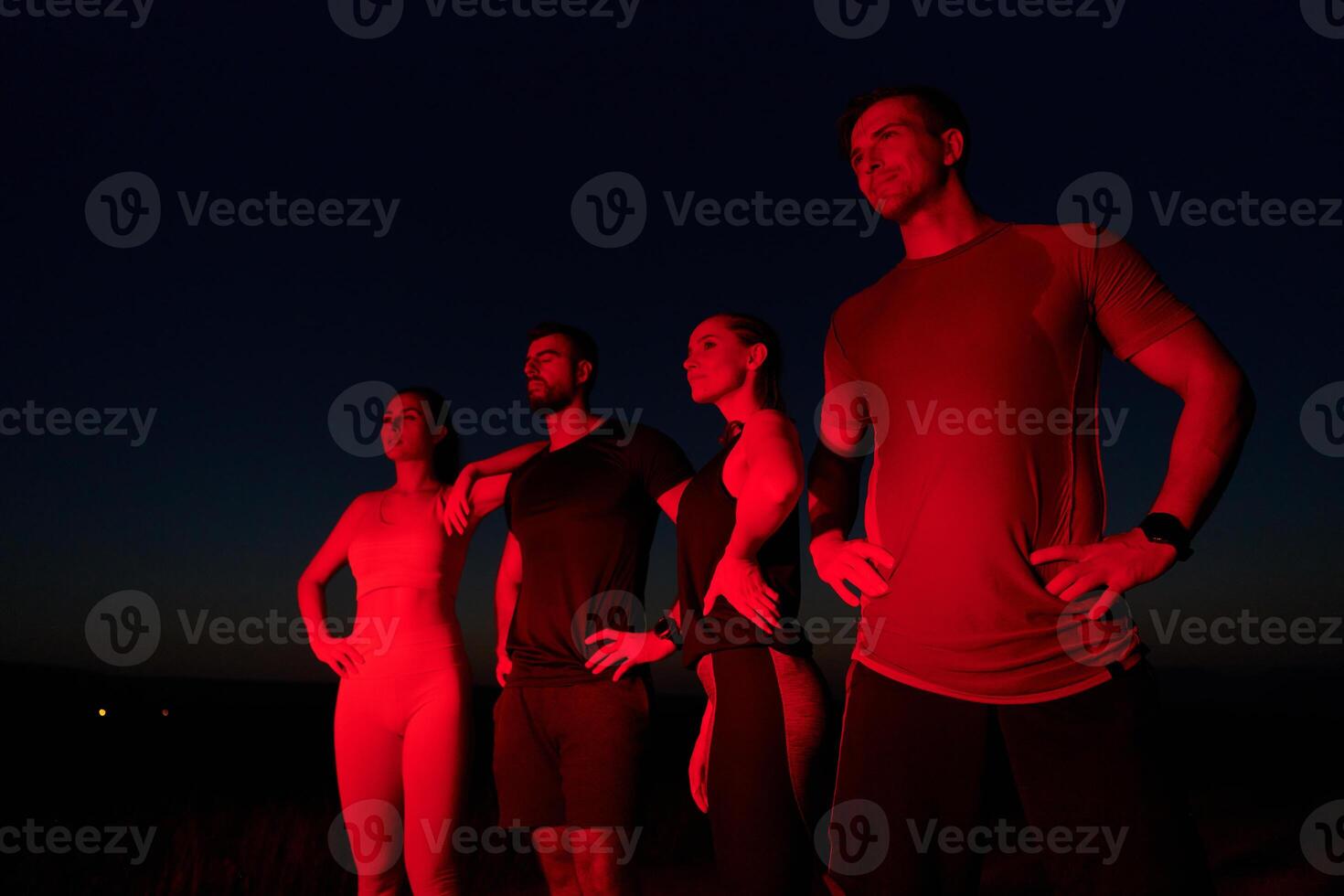 Diverse Athletes Unwind. Post-Marathon Rest Under Red Nighttime Glow. photo