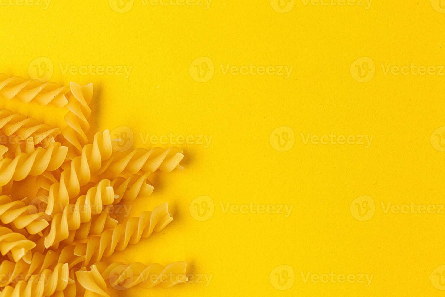 Different types and shapes of dry italian pasta on a yellow background photo