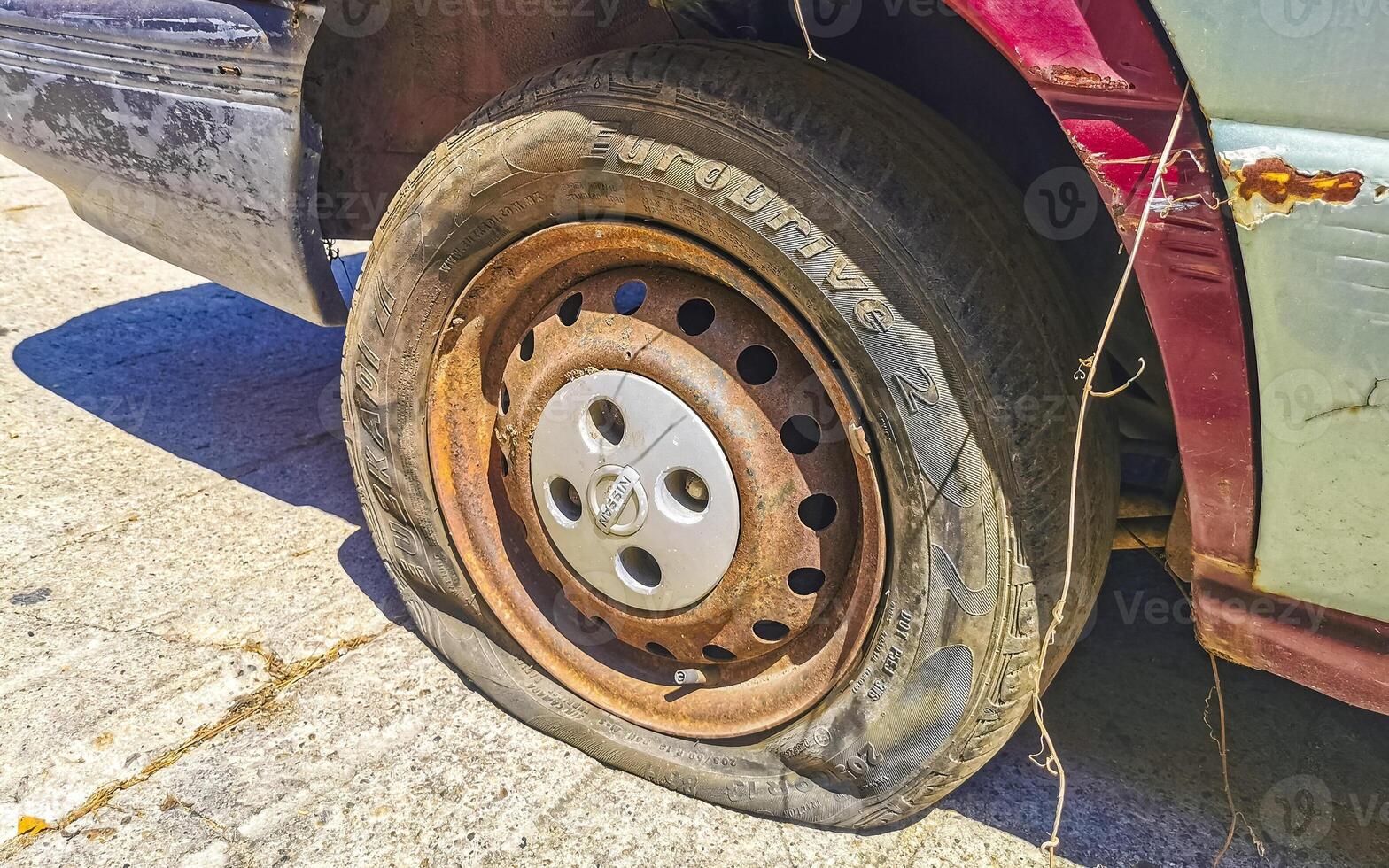 Flat rusted old tire on the car Puerto Escondido Mexico. photo
