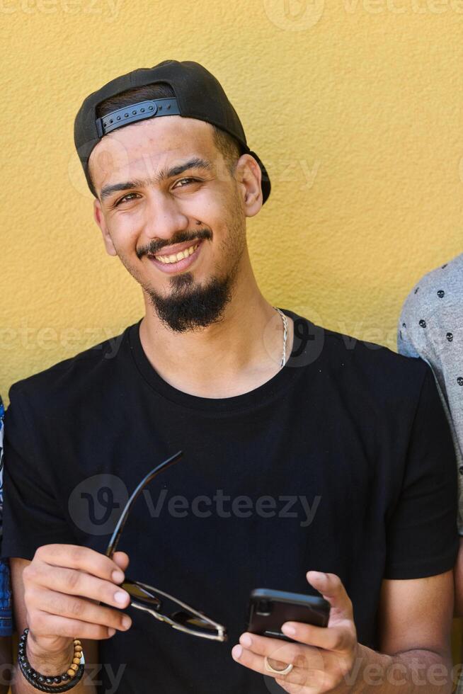 Close Up Portrait of Smiling Sudanese Teenager with Broad Smile, Chin, and Cap Using Smartphone photo