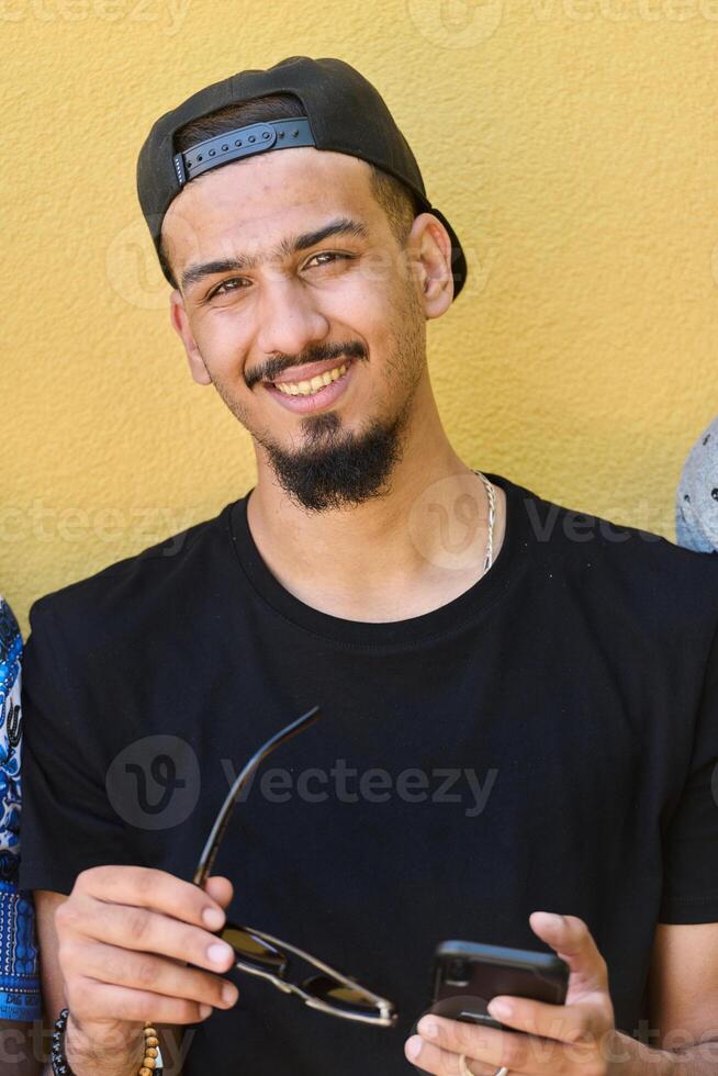 Close Up Portrait of Smiling Sudanese Teenager with Broad Smile, Chin, and Cap Using Smartphone photo