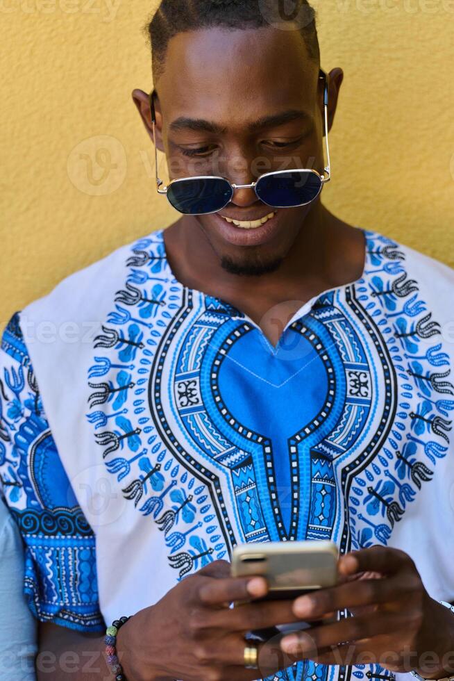 African American Teenager in Traditional Sudanese Attire Engaged with Smartphone photo