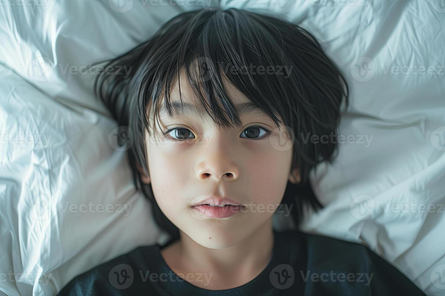 Portrait of a 10 year old Japanese child lying on the bed, looking at the camera from directly above, with scared face and gloomy mood photo