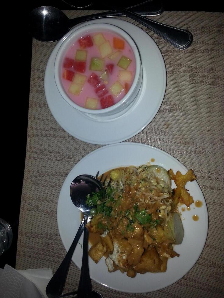 A plate of tofu bean sprouts and a bowl of fruit ice were served on the table photo