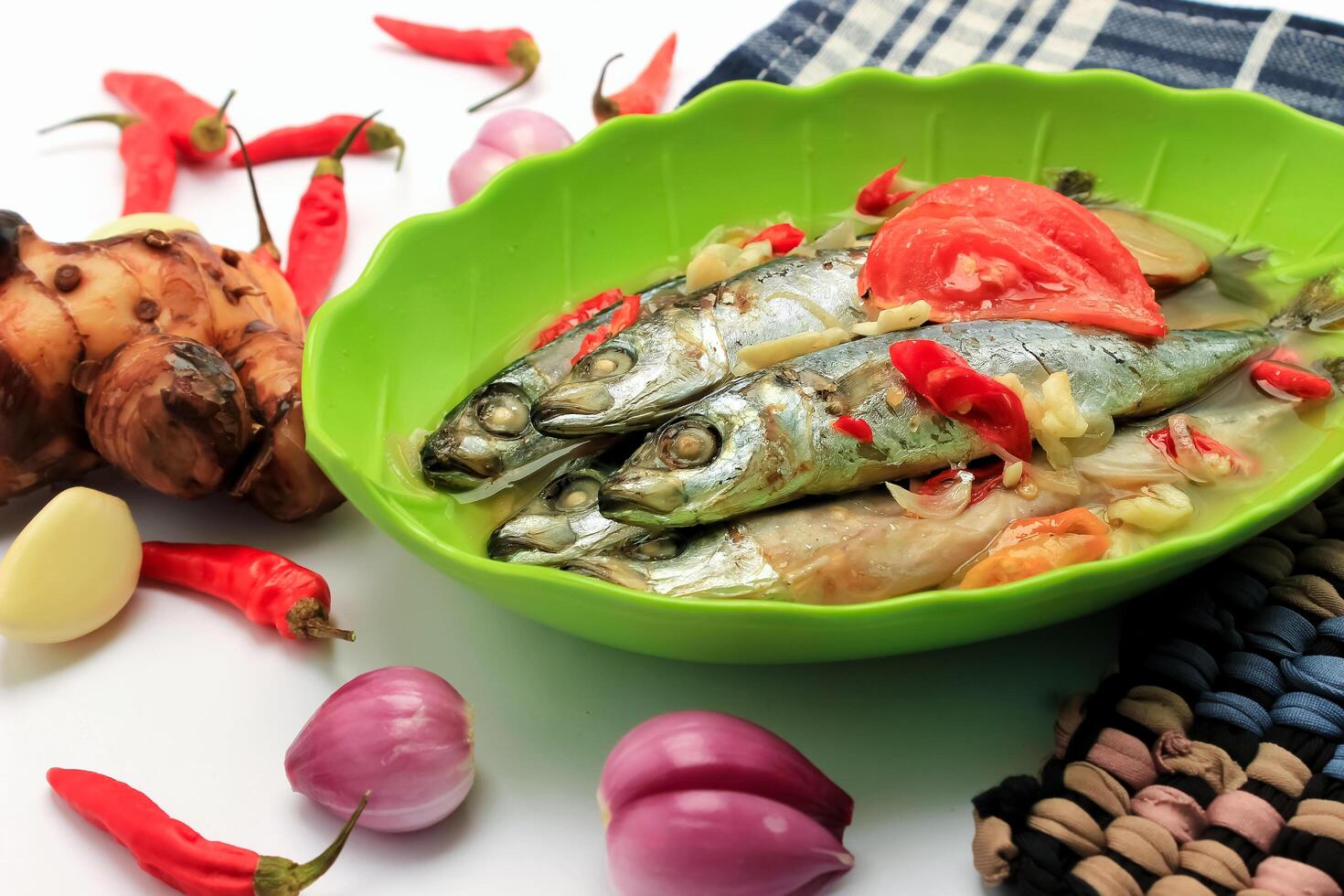 Boiled fish contain fish, sauce, chilies, tomatoes, spices, onions served in a bowl isolated on white background photo