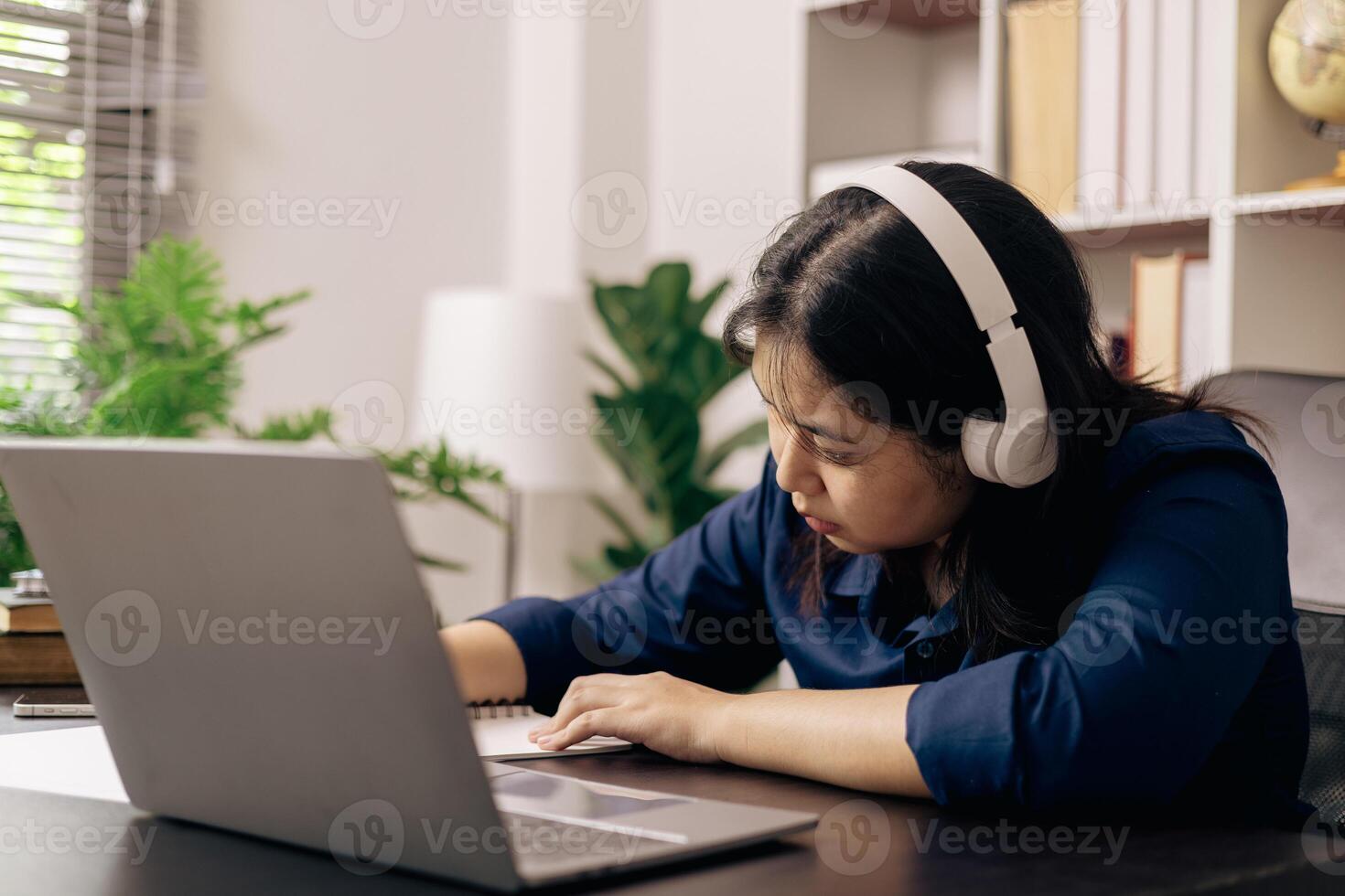 Happy student, studying for MBA exam, takes advantage of distance learning to attend school from home, balancing training and class. Woman studies book and research for online academy using laptop. photo