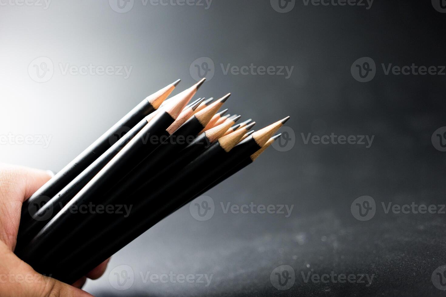 Hand holding black pencil photo