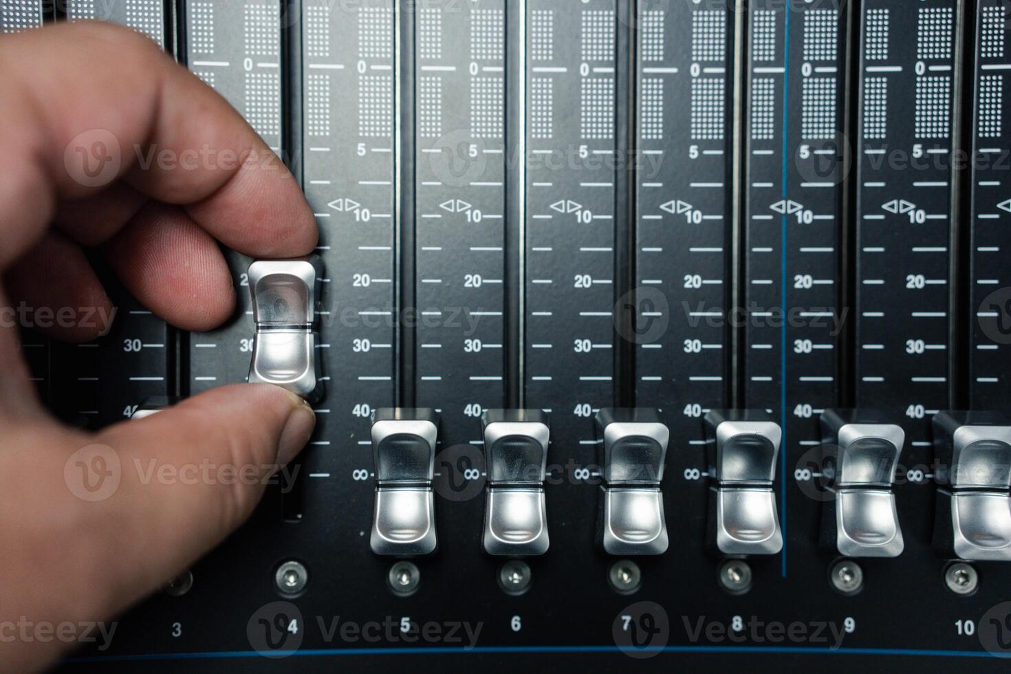 Person moving slider on professional sound mixing desk photo