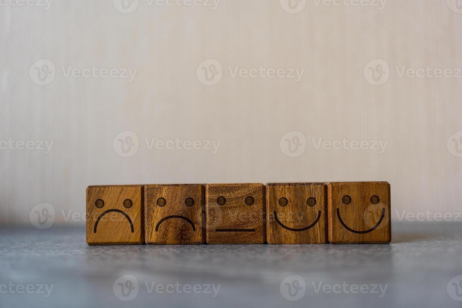 Satisfaction feedback in form of face emoticon on wood block photo