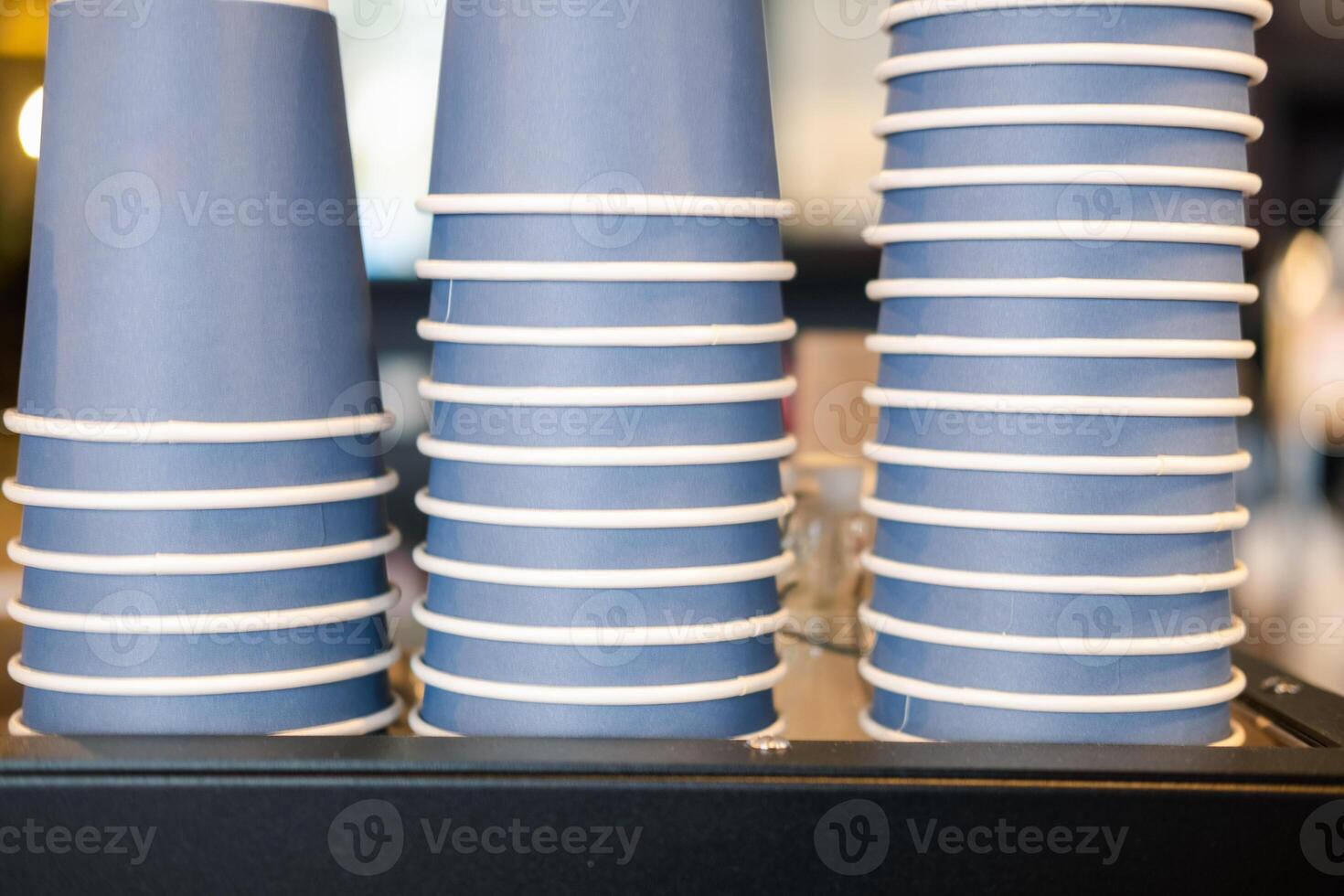 Pile of blue paper drinking cups neatly organized on coffee machine at a cafe. photo
