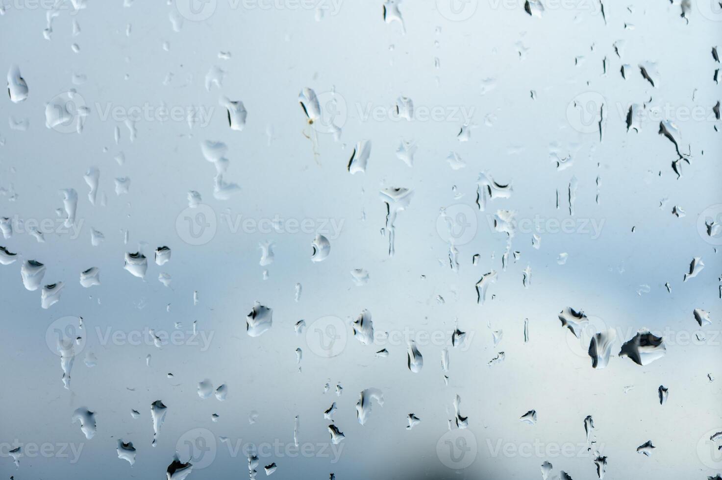 Glass with rain drops against gray background. 1 photo