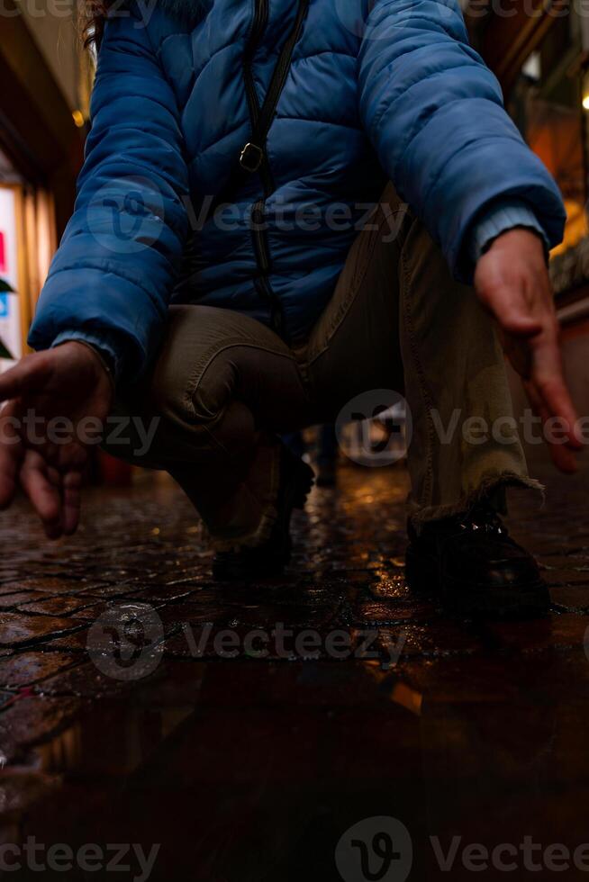 female feet in blue sneakers are reflected in a puddle of a city street photo