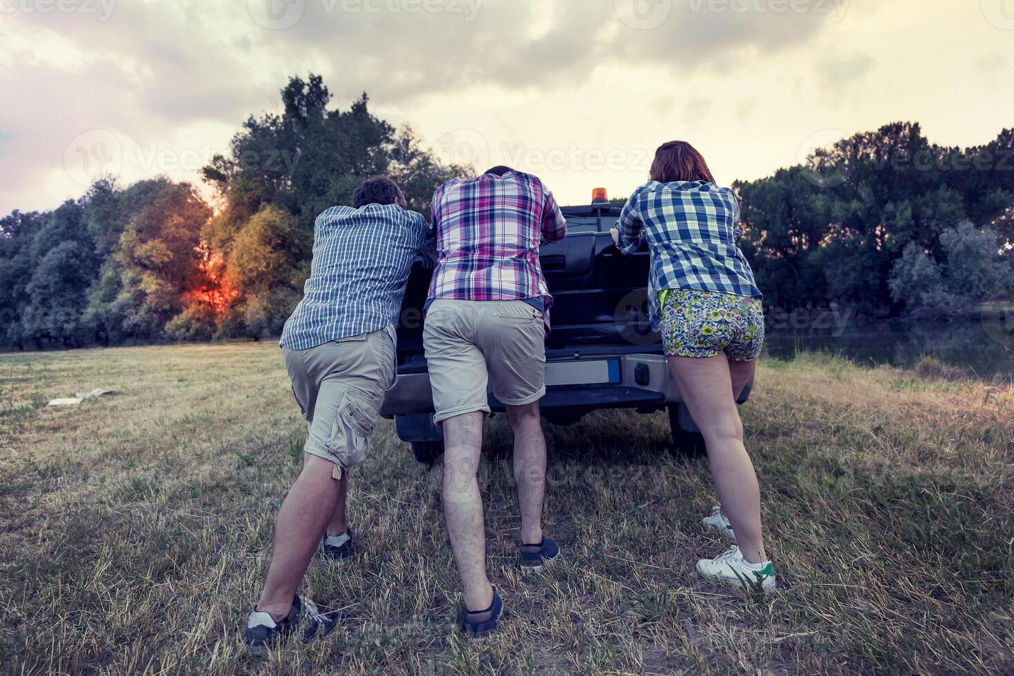 group of friends pushing the broken car photo