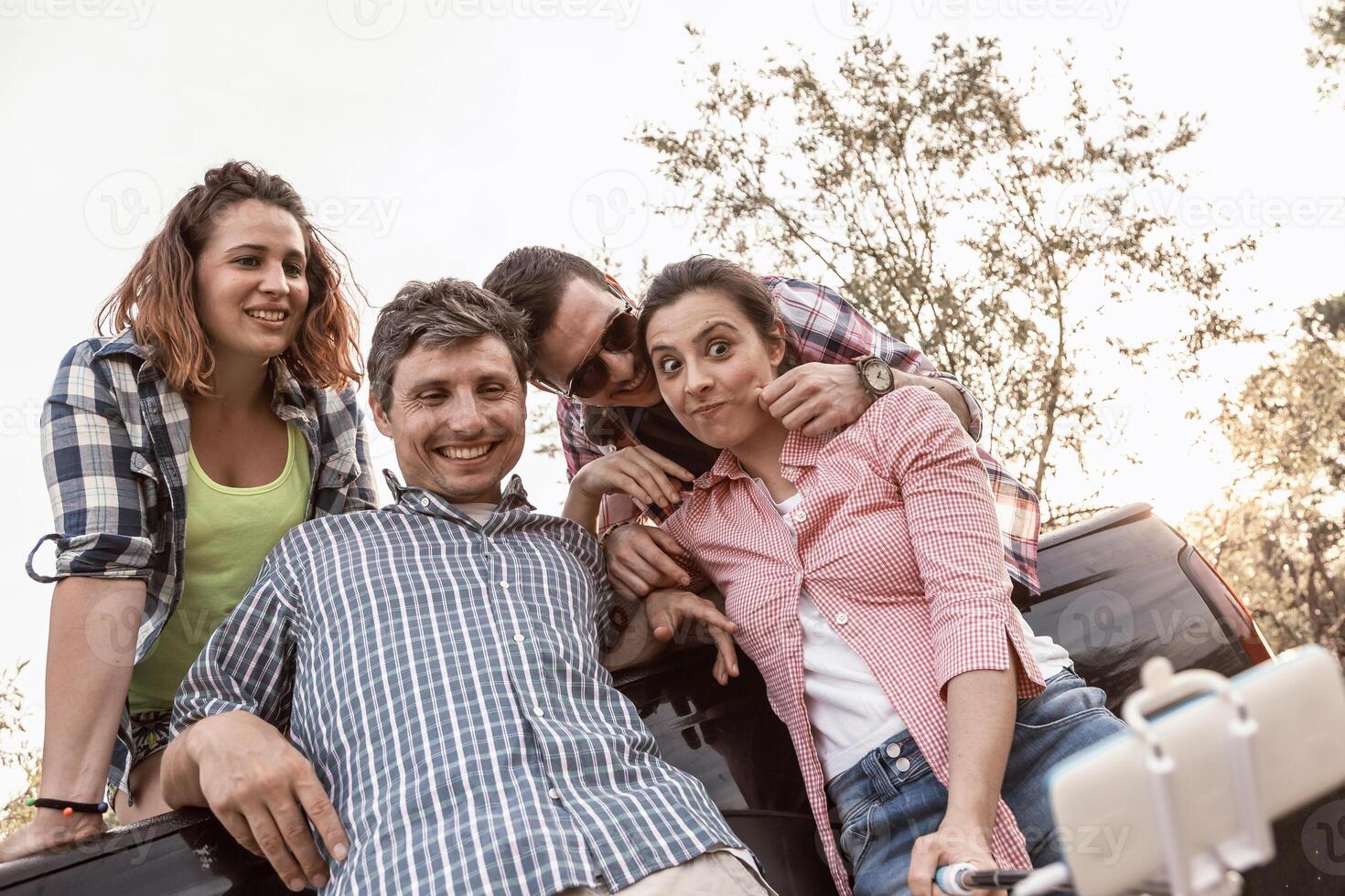 Happy group of millennial people takes a selfie outdoor sitting in a car photo