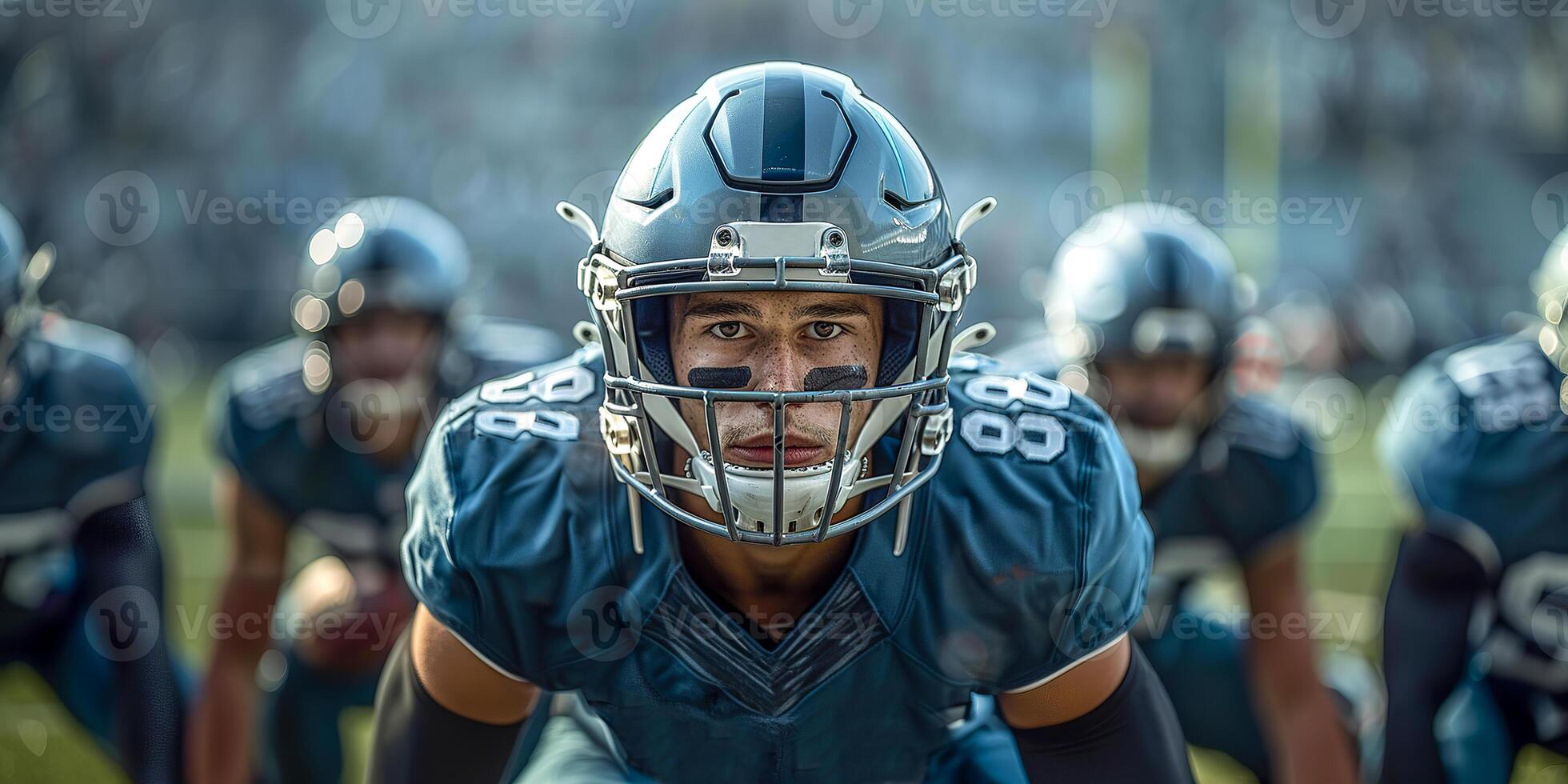 American football player in a gray helmet and a green uniform stands at the ready to play the ball photo