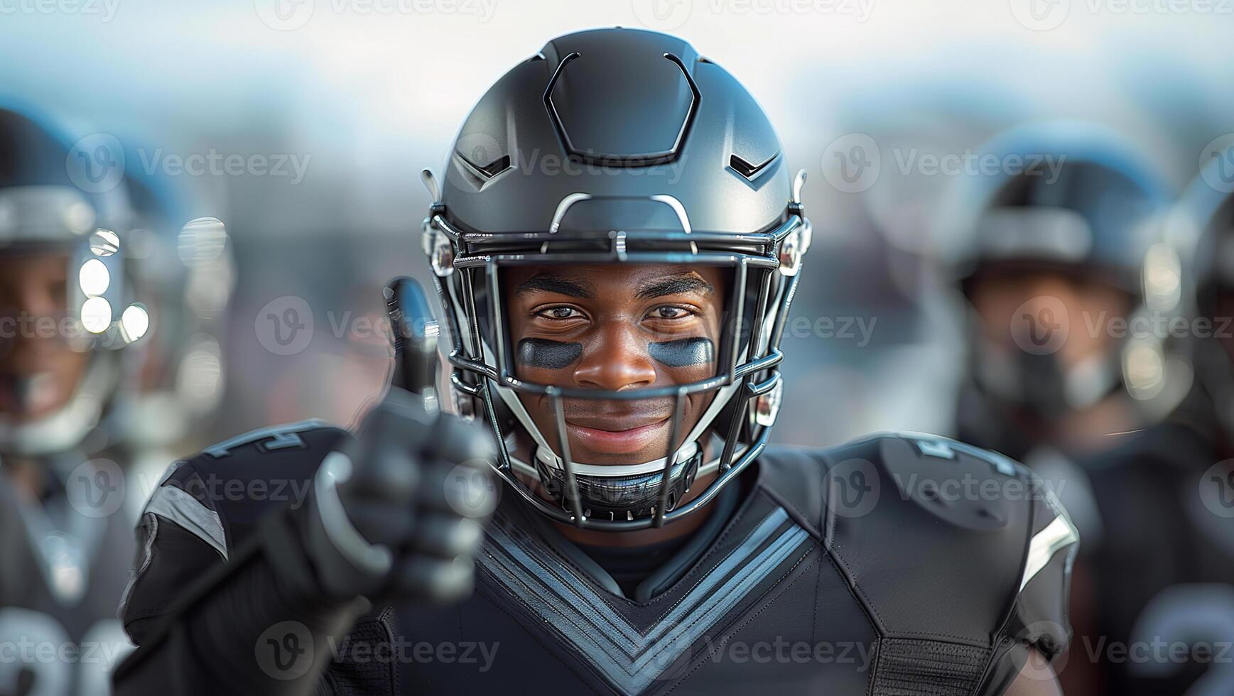American football player in a black helmet and uniform smiles and gives a thumbs up photo