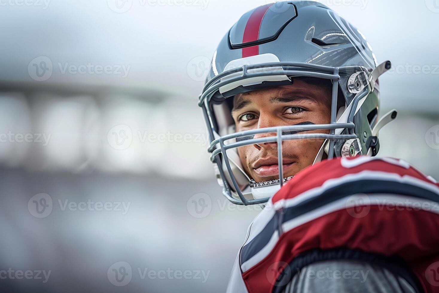 American football player in a gray helmet and red uniform stands smiling and looks to the left. Copy space photo
