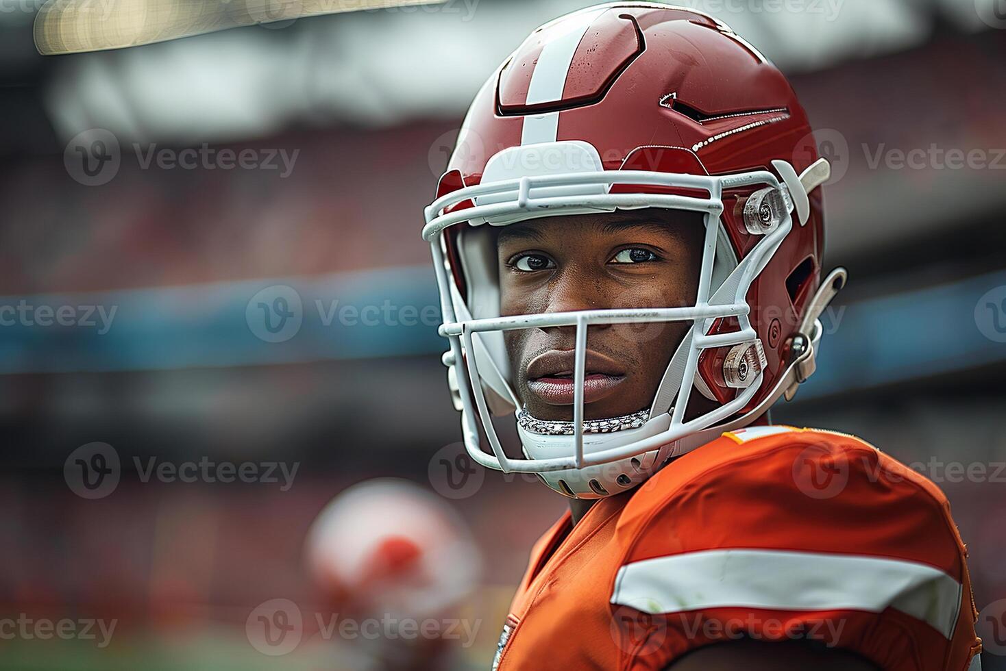 American football player in a red helmet and uniform stands against the background of the stands. Copy space photo