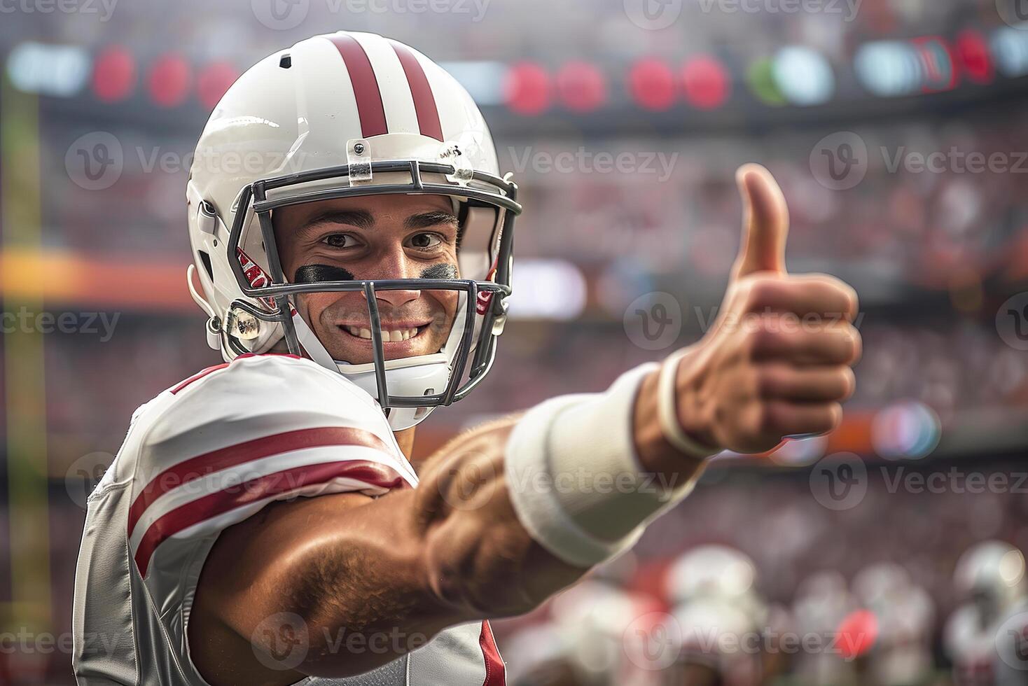 American football player in a white helmet and uniform gives a thumbs up with his right hand. On the background of the arena grandstand photo