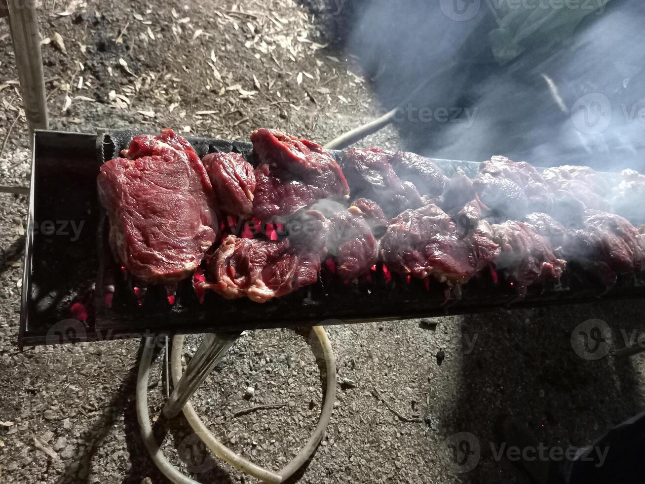 Steaks on a barbecue in the process of cooking photo