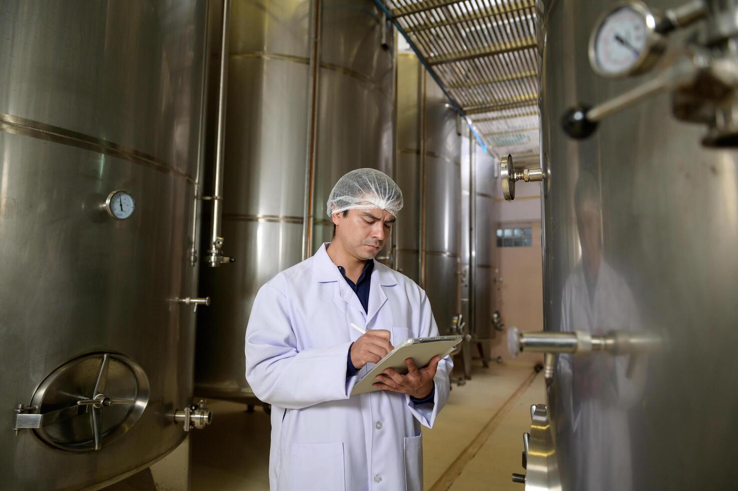 Professional winemaker controlling wine making process and quality at winery factory photo