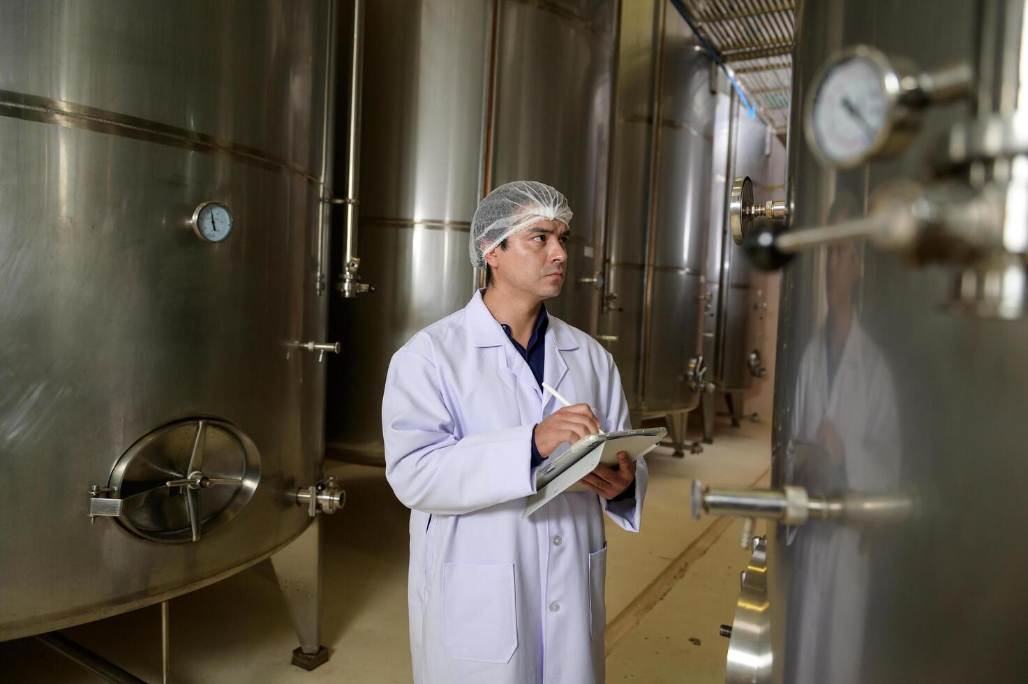 Professional winemaker controlling wine making process and quality at winery factory photo