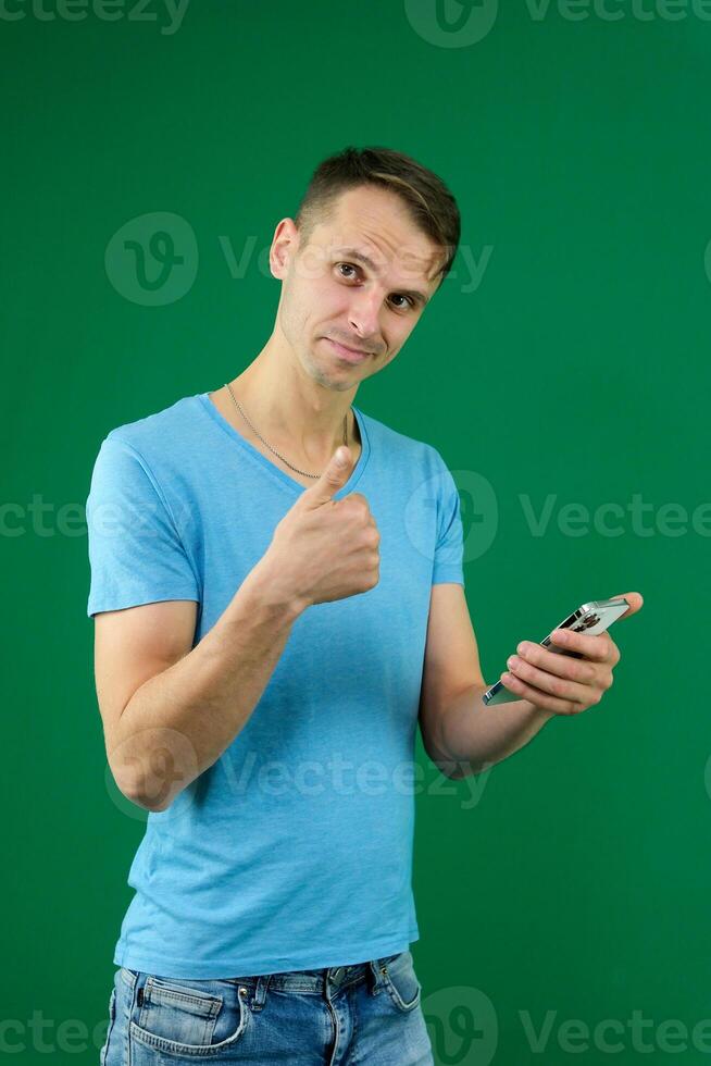 Young promoter man wear shirt white t-shirt point index finger camera on you indicate index finger aside on workspace area copy space mock up isolated on plain pastel green background studio photo