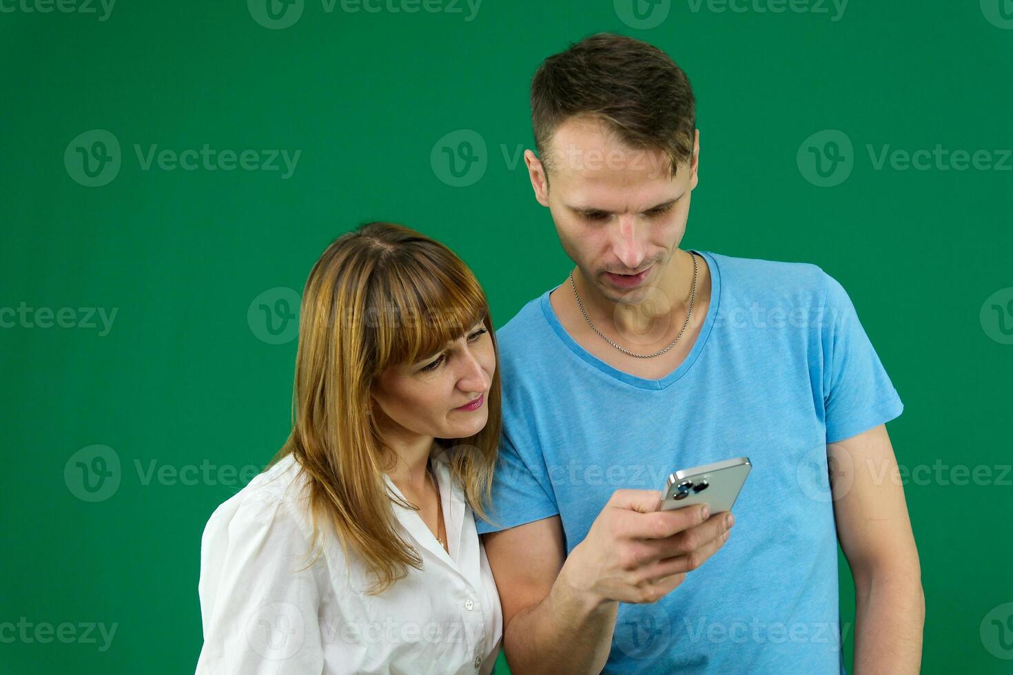 phone call search on the Internet to solve problems a man helps a woman on a green background chromakey spend time in office in nature blue T-shirt white jacket light people touchpad news feed gadget photo