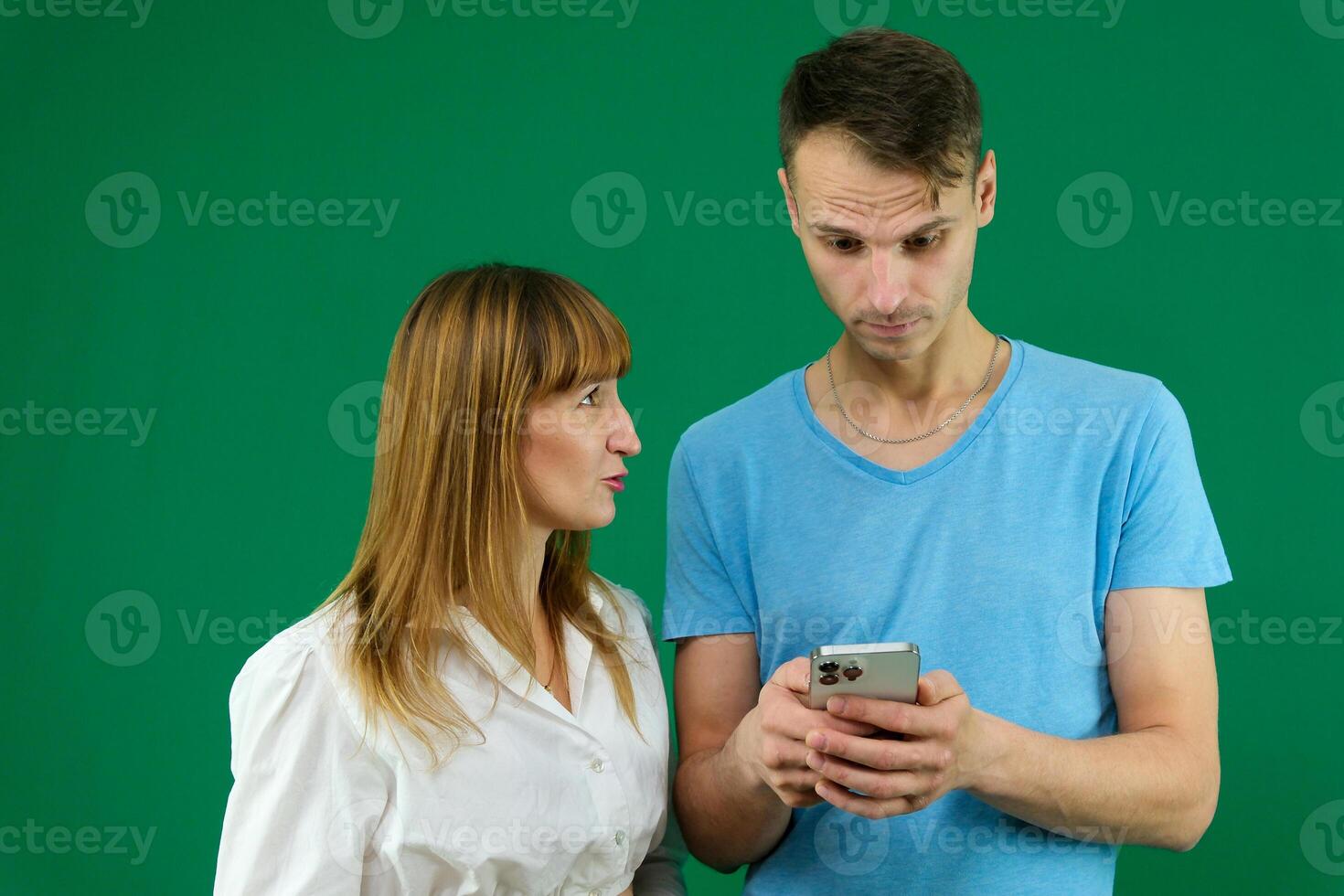 Picture of a young couple watching a funny on mobile phone, posing on isolated background photo
