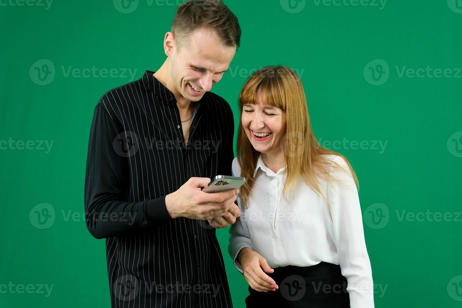 man and woman with gadgets tablet phone in hands on green background talking laugh holding meeting learning to work on Internet flirting relationships flirting couple solving issue positive emotions photo