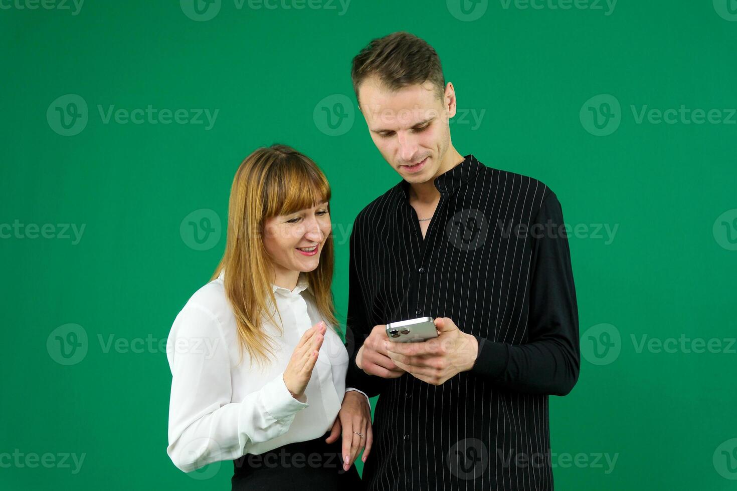 man and woman with gadgets tablet phone in hands on green background talking laugh holding meeting learning to work on Internet flirting relationships flirting couple solving issue positive emotions photo