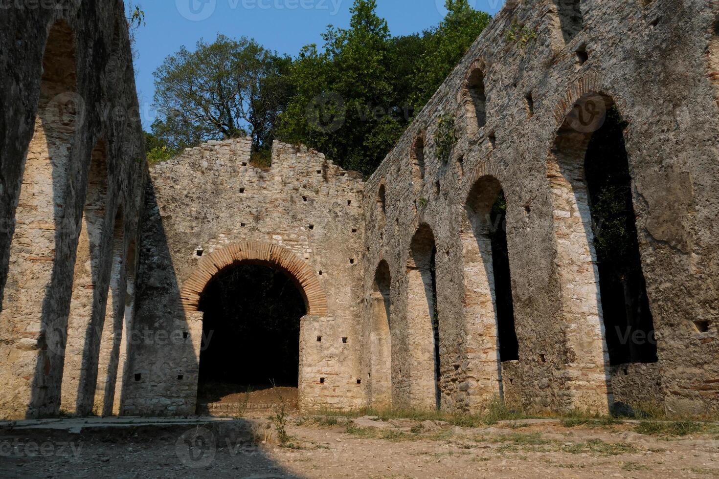 Ruins of the Great Basilica in Butrint National Park, Buthrotum, Albania. Triconch Palace at Butrint Life and death of an ancient Roman house Historical medieval Venetian Tower surrounded photo