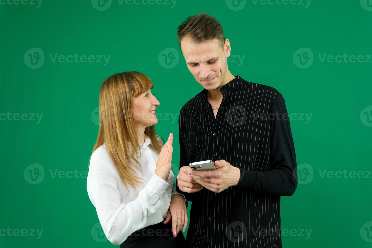 man and woman with gadgets tablet phone in hands on green background talking laugh holding meeting learning to work on Internet flirting relationships flirting couple solving issue positive emotions photo