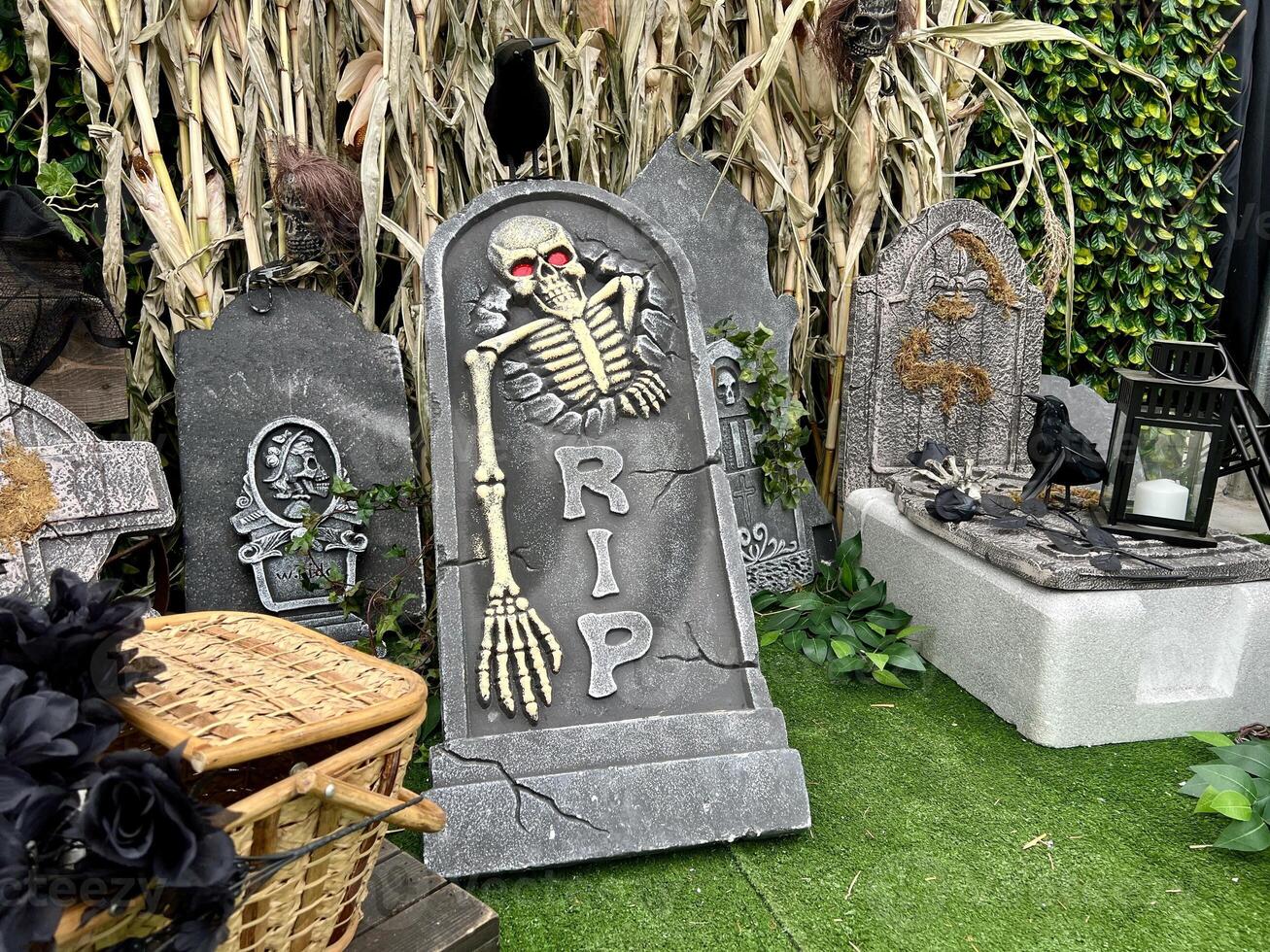 tombstone halloween slabs Skeletons head and bones Reeds on artificial green grass in the background It's written on the stone RIP There are also broken boards, spiders, baskets and crosses. photo