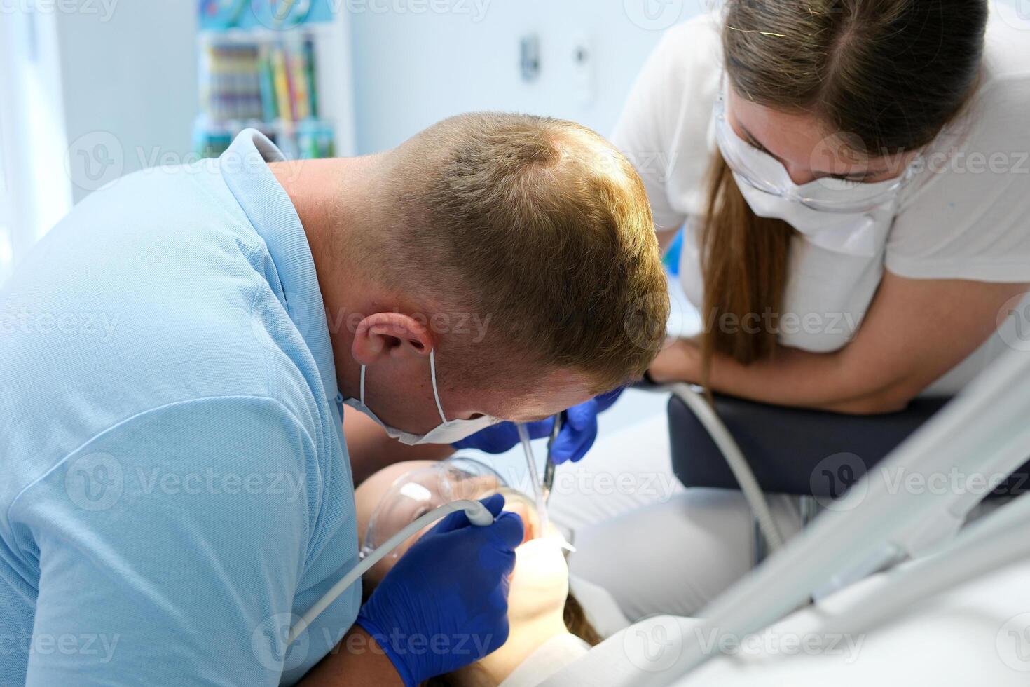 Professional tooth cleaning Dentist with assistant under microscope treats the patient's teeth. Modern progressive dentistry. photo
