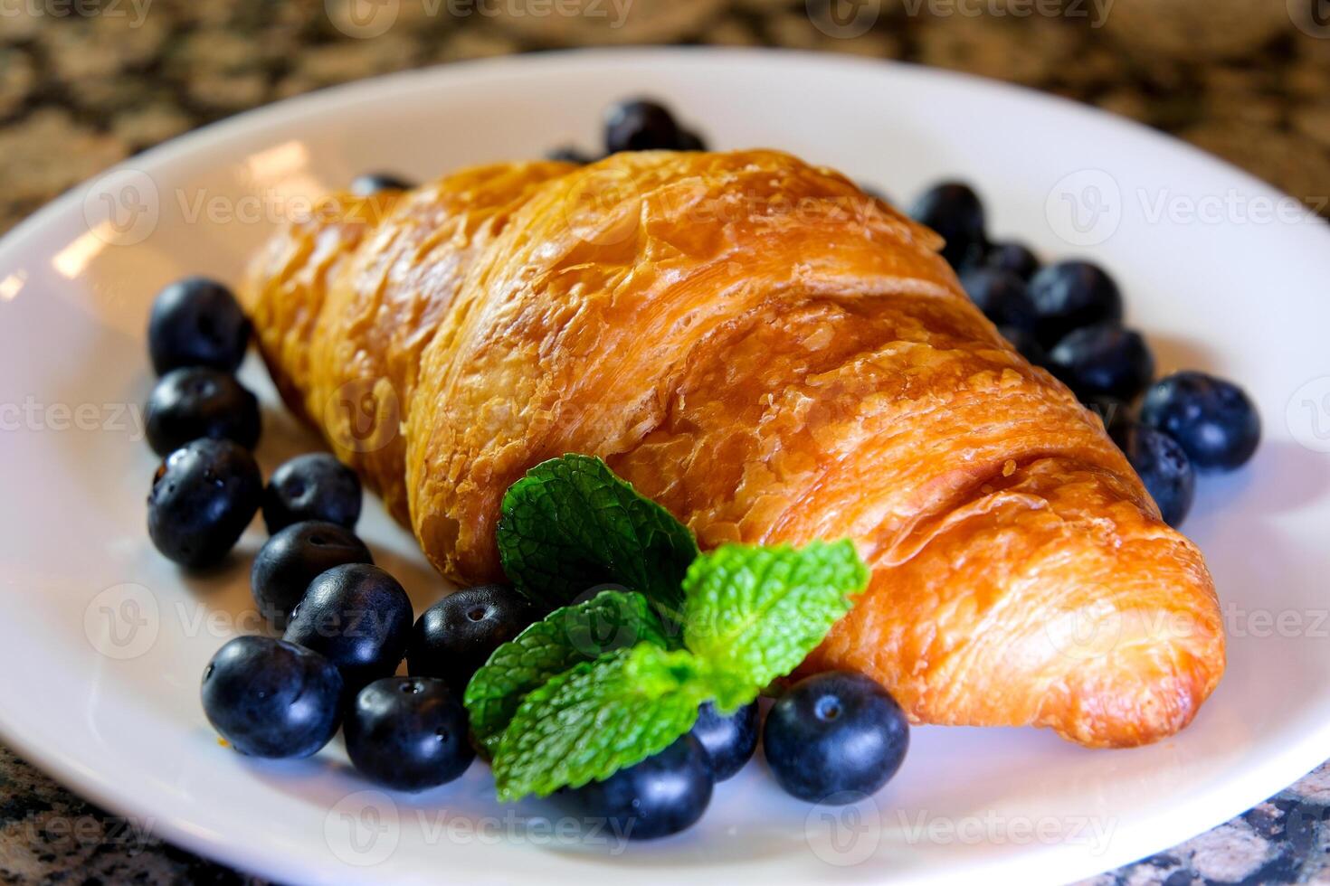 Extreme close up powdered sugar is poured onto croissants with blueberry. strainer with flour or sugar, which is sprinkled with baked goods before serving. Breakfast or dessert cooking concept photo