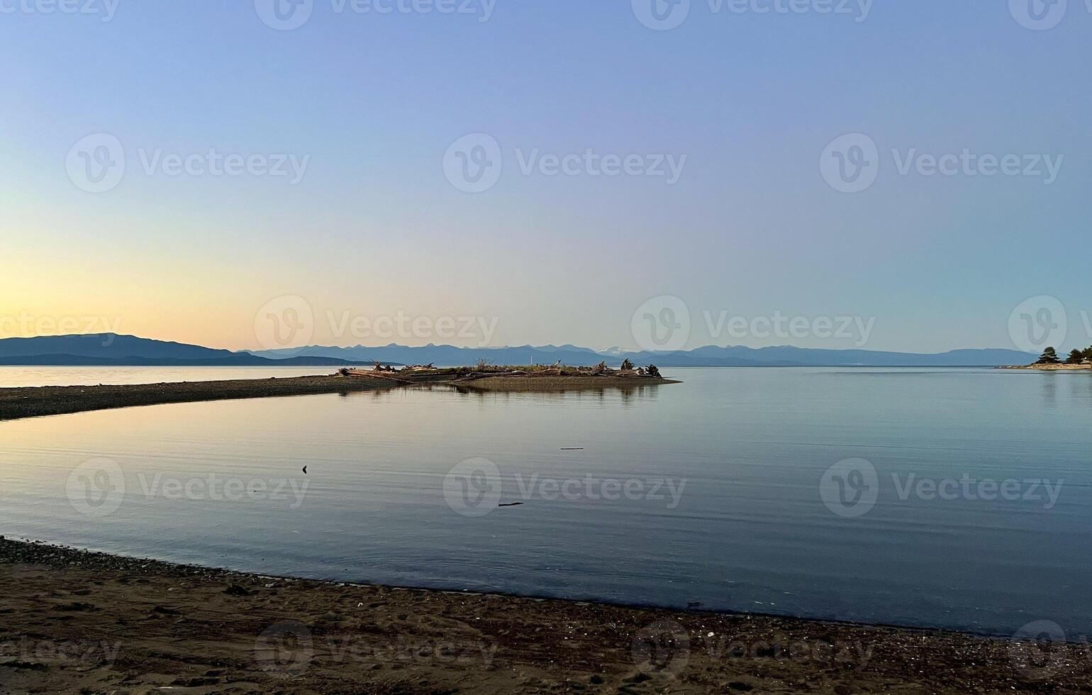 sunset on the Ocean Calmness calm sea on Vancouver Island resting in trailers on the shore bright colors of dark blue orange stripe on the horizon from the sun rich space for text travel advertising photo