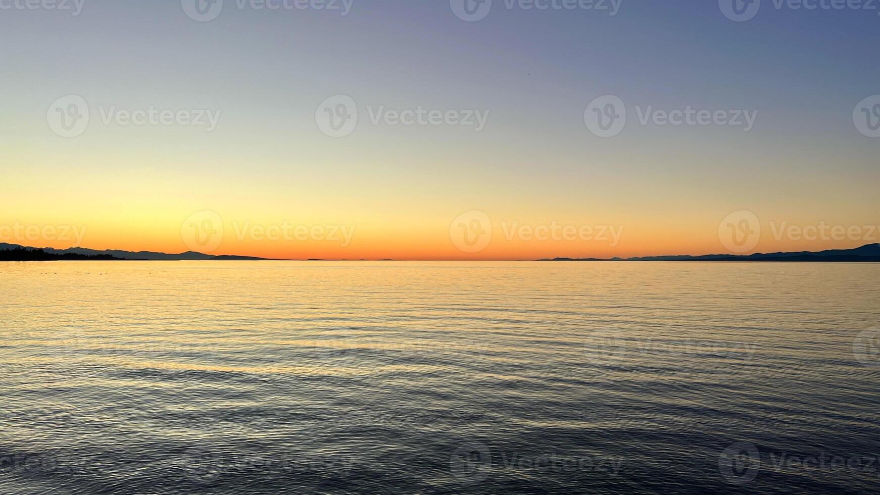sunset on the Ocean Calmness calm sea on Vancouver Island resting in trailers on the shore bright colors of dark blue orange stripe on the horizon from the sun rich space for text travel advertising photo