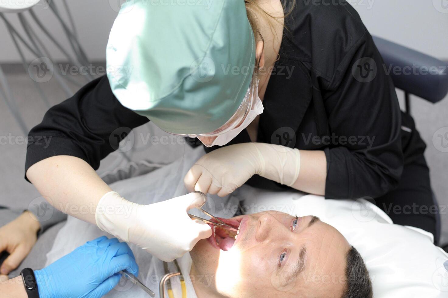 Dentist doctor works with a patient close-up remove teeth photo