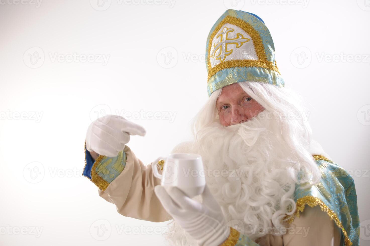 Photo of retired positive man hold mug delicious tasty beverage eggnog hot chocolate tea enjoy spending time Sinterklaas portrait. white background. Dutch Santa Claus St Nicholas christmas new year