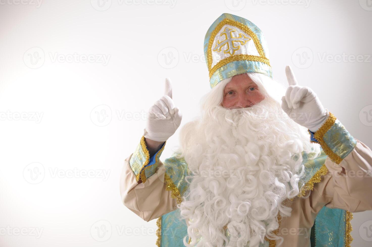 white rich beard and golden blue suit of St. Nicholas raised two fingers up listen to me look here attention Sinterklaas portrait positive emotions Dutch Santa Claus St Nicholas christmas new year photo