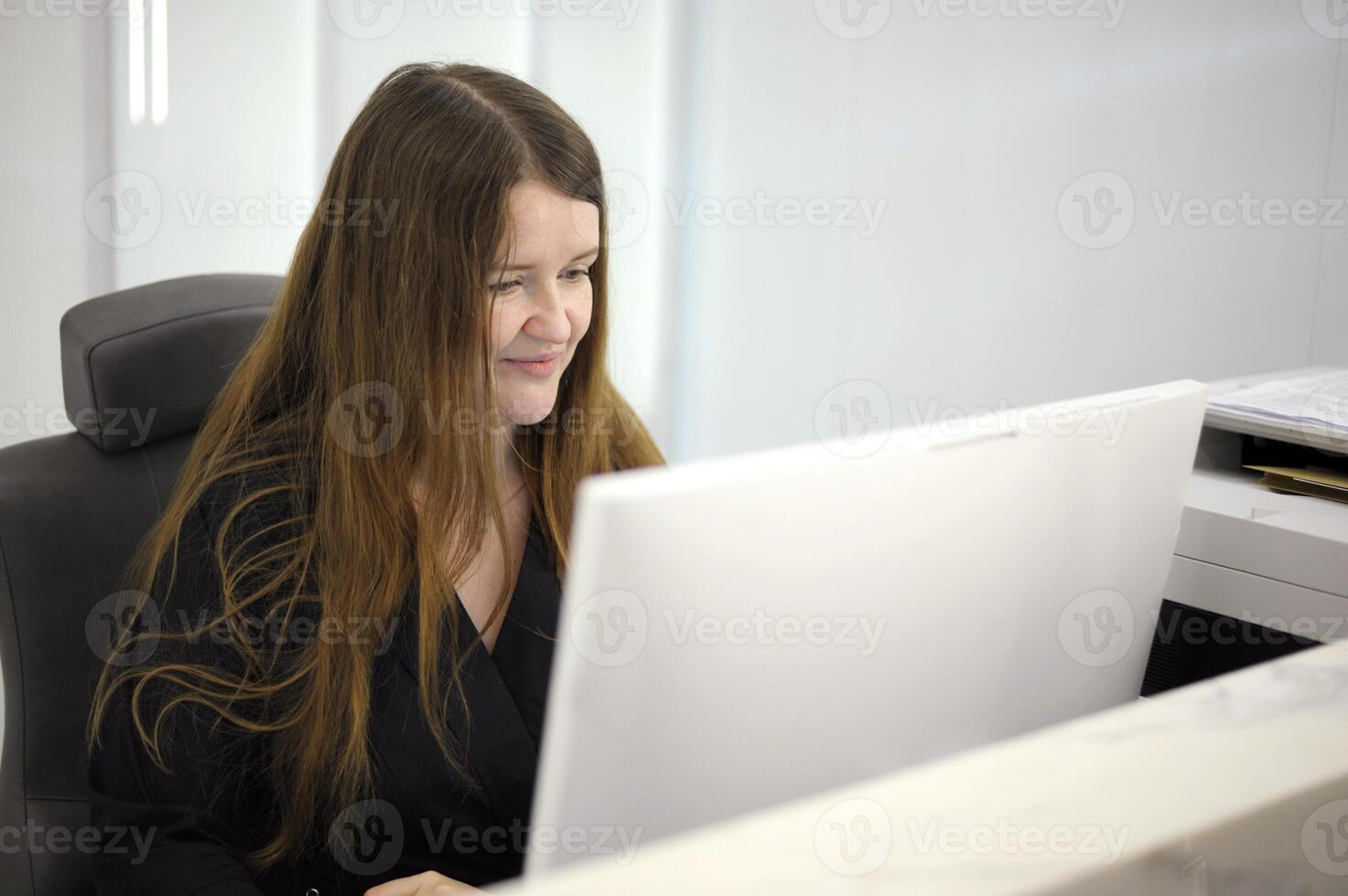 long hair black clothes white computer laptop young woman sits at a computer at the reception of a white light office hospital dentistry any computer programmers photo