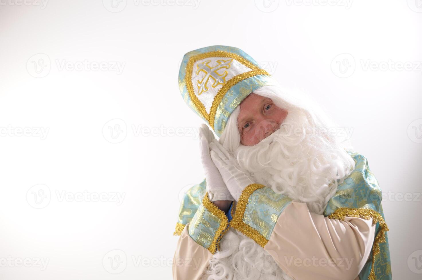 Santa Claus put his hands on his cheek turquoise and gold suit long white beard and a hat with a cross saint looks Dutch Santa Claus St Nicholas christmas new year photo